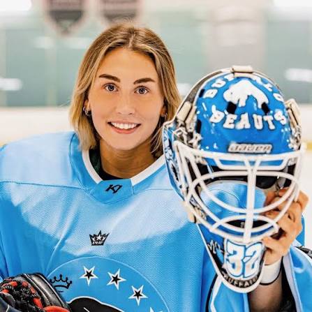 Kassidy Sauvé smiling, holding her Buffalo Beauts goalie mask